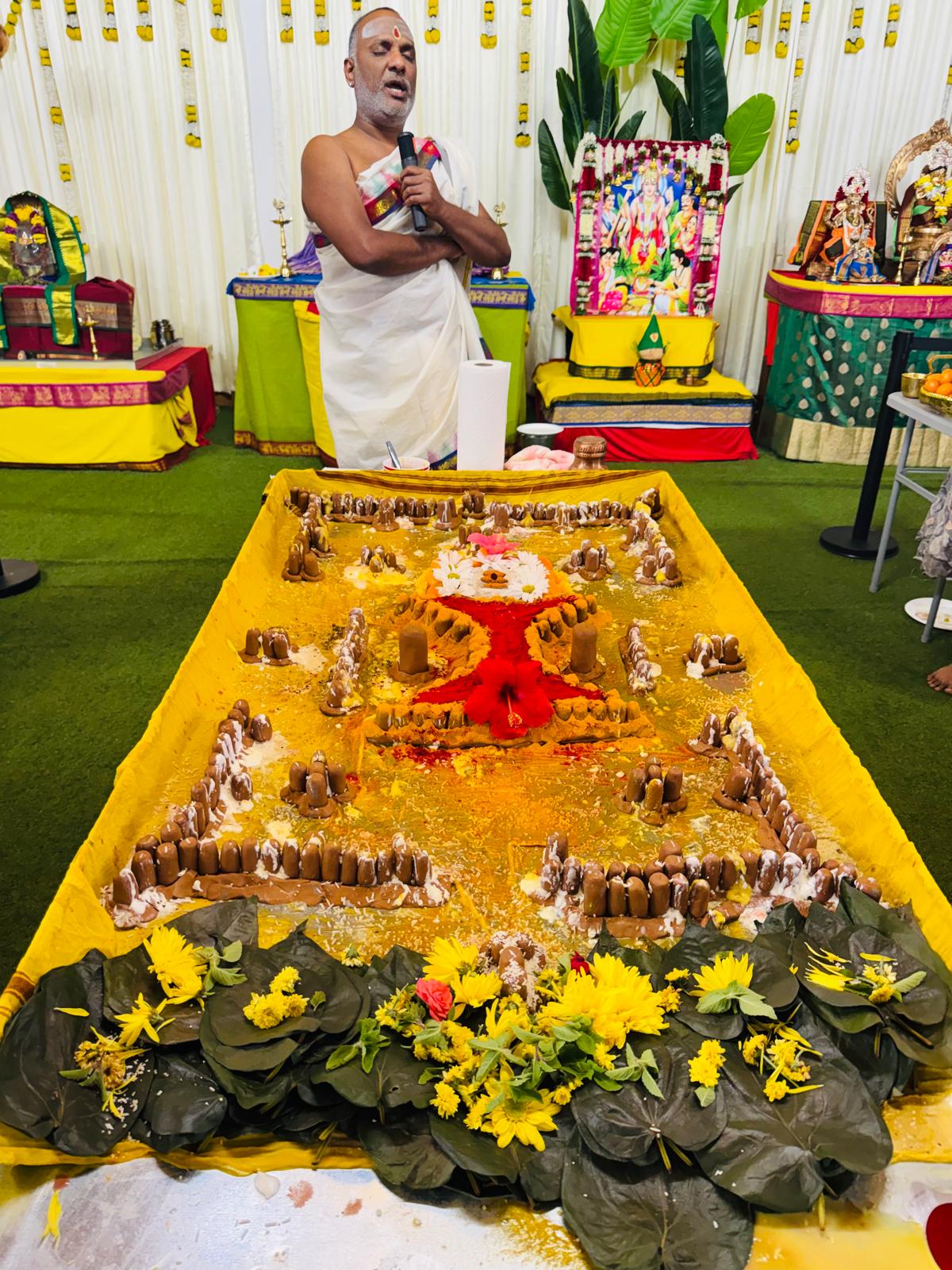 A priest and devotees conducting Maha Linga Archana, with a Shiva Linga adorned with flowers, lamps, and ritual offerings.